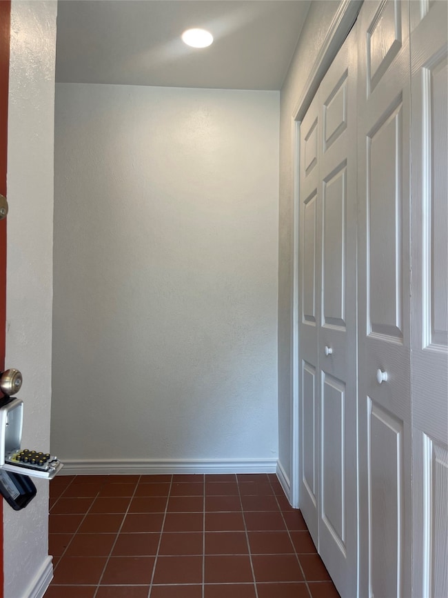 Hallway with dark tile patterned flooring and a textured wall