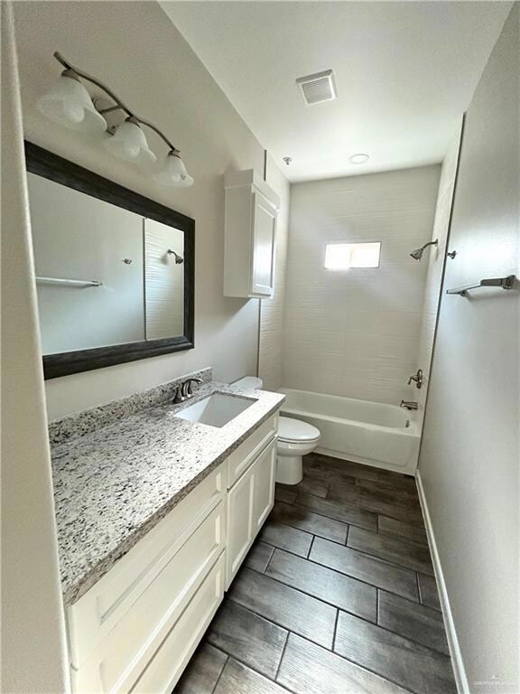 Full bathroom with vanity, toilet, baseboards, tub / shower combination, and visible vents