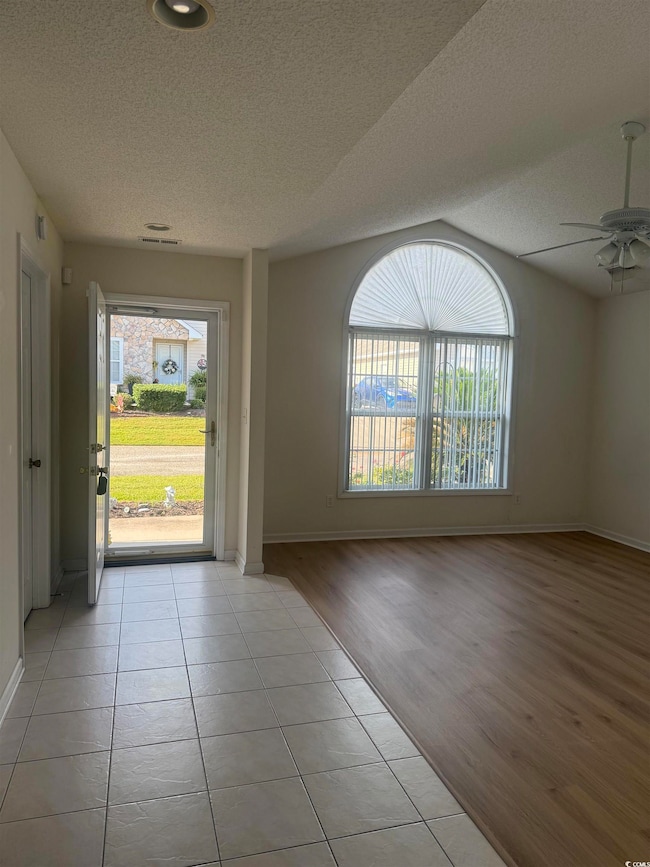 Foyer featuring light tile patterned flooring, plenty of natural light, a textured ceiling, and ceiling fan