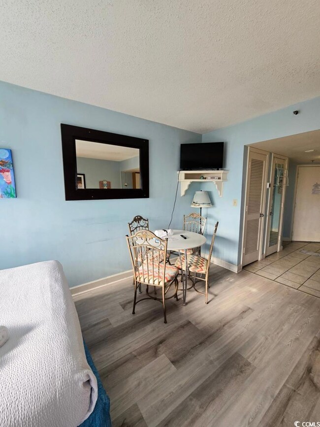 Dining area featuring a textured ceiling, wood finished floors, and baseboards
