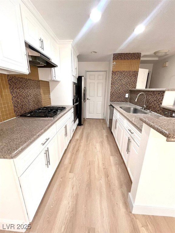 Kitchen featuring a sink, light wood finished floo