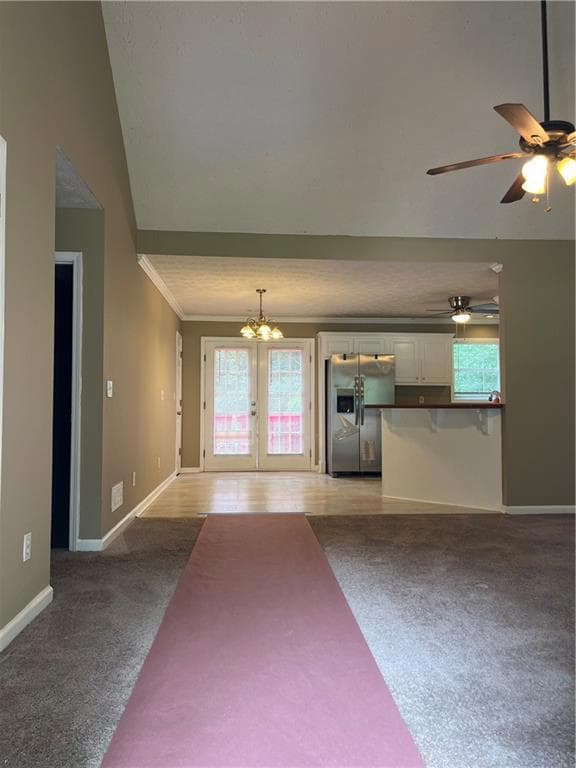 Unfurnished living room with light colored carpet, crown molding, baseboards, french doors, and plenty of natural light