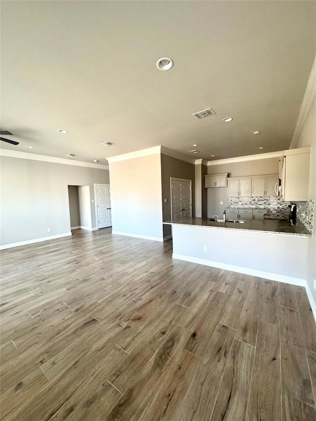 Unfurnished living room with ornamental molding, wood finished floors, and recessed lighting
