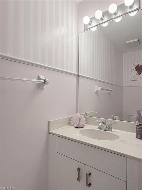 Bathroom featuring wallpapered walls and vanity