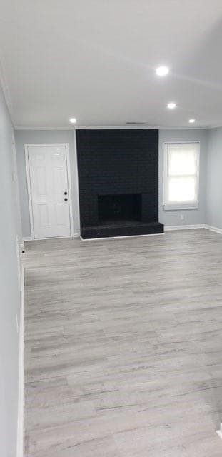 Unfurnished living room featuring light wood-style flooring, a fireplace, recessed lighting, and ornamental molding