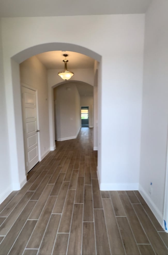 Spare room with arched walkways and wood finished floors