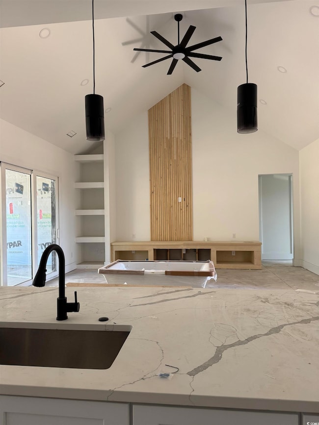 Kitchen with light stone counters, a sink, hanging