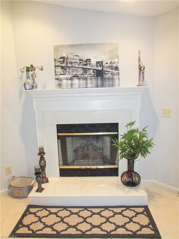 Living Room Fireplace Features Gas Logs, Marble Hearth & Trim Panels, Glass Firebox Enclosure & White Dental Detailed Wood Mantel.
