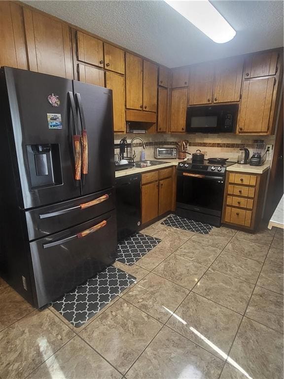 Kitchen with refrigerator with ice dispenser, light countertops, brown cabinetry, and a textured ceiling