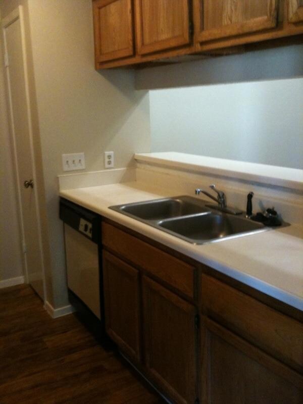 Kitchen with brown cabinetry, dark wood-style flo