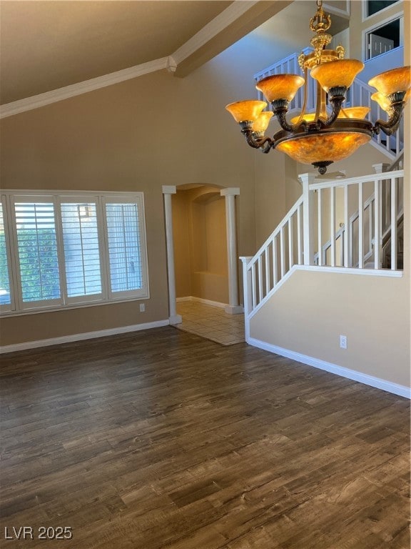 Unfurnished living room featuring stairs, a chandelier, crown molding, dark wood-style floors, and arched walkways