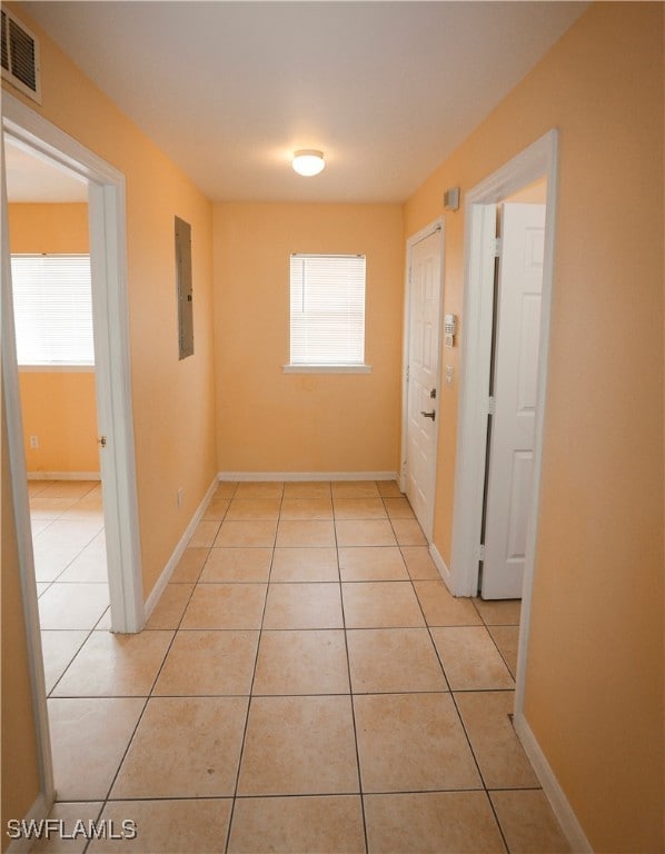 Hallway with electric panel, visible vents, basebo