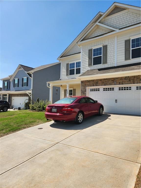 View of front of house with concrete driveway, sto