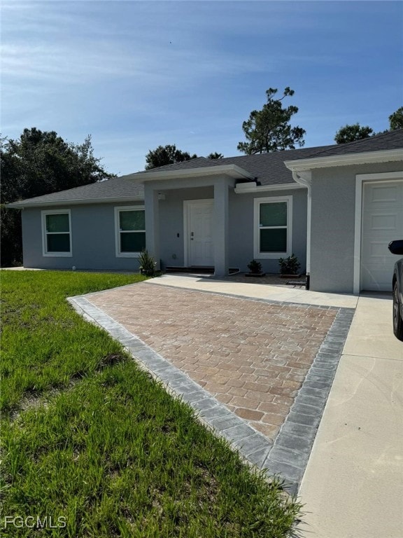 Ranch-style house with stucco siding, a front lawn, a shingled roof, and an attached garage