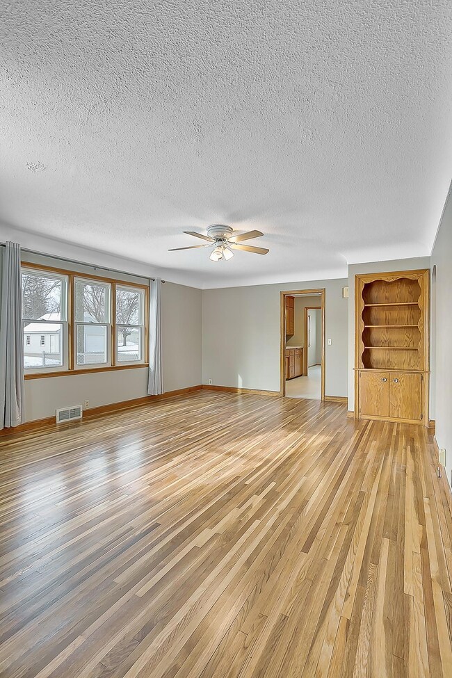 Freshly refinished hardwood floors showing off coved ceilings and built-in