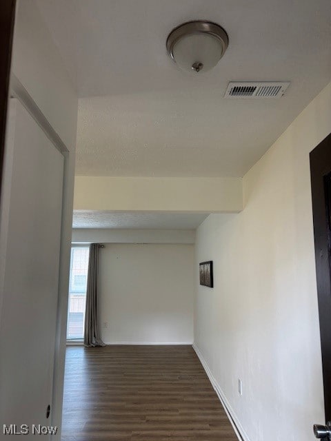 Corridor featuring dark wood-type flooring and baseboards