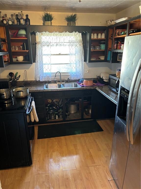 Kitchen featuring a sink, fridge, range, open shel
