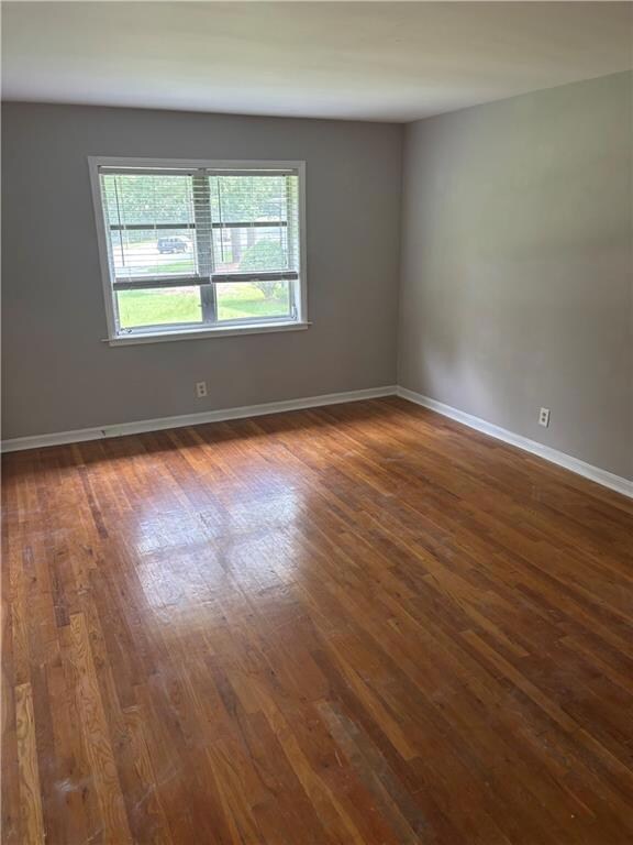 Unfurnished room with dark wood-style flooring and baseboards