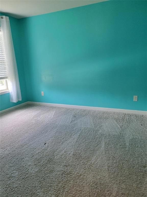 Spare room featuring carpet and baseboards
