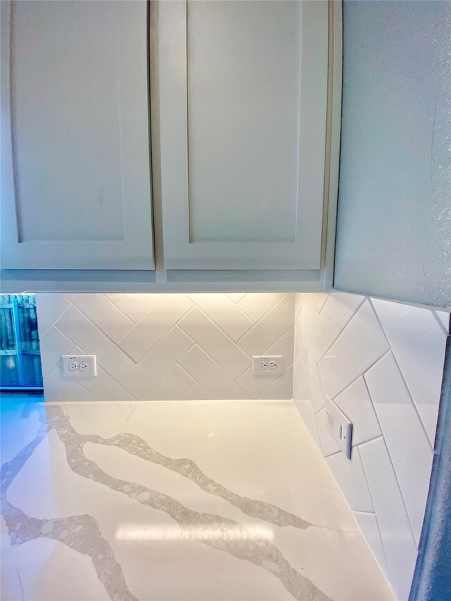Painted white cabinets, Marcella Quartz, herringbone 4x12 subway backsplash, and undermount lighting.