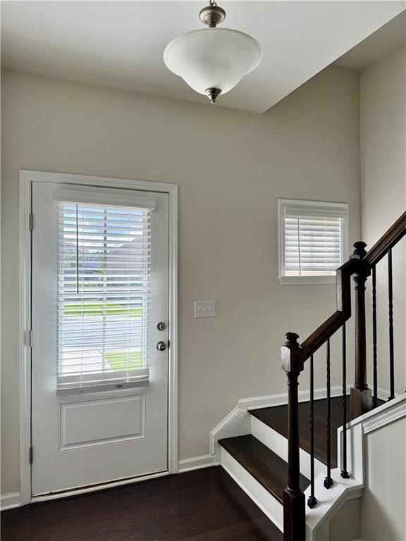 Doorway with stairs and dark wood-style floors