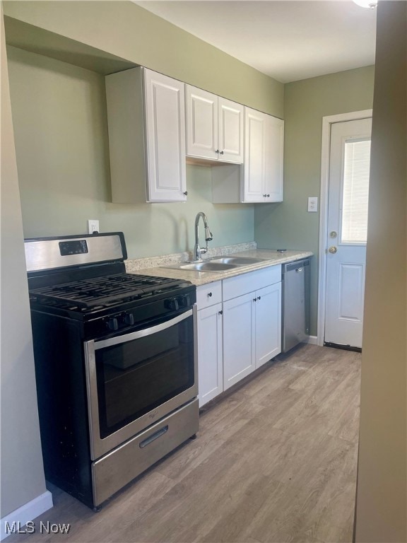 Kitchen with stainless steel appliances, white cabinetry, and light wood-type flooring