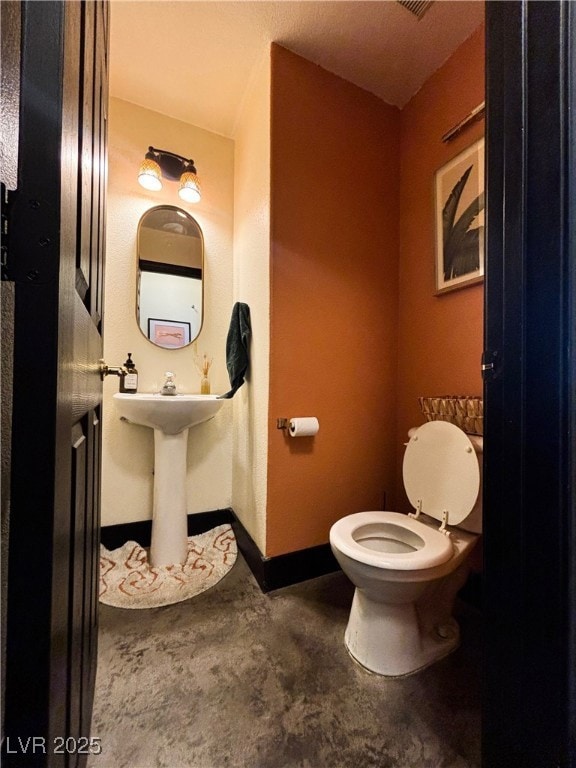 Bathroom featuring toilet, unfinished concrete flo