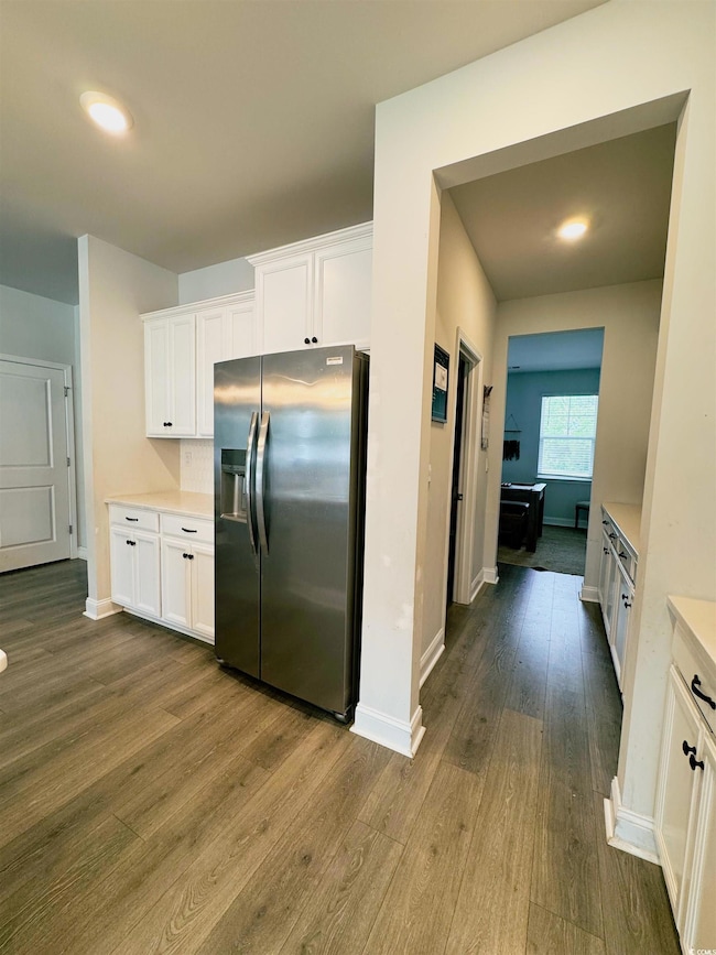 Kitchen with white cabinets, stainless steel refrigerator with ice dispenser, and dark wood-style floors