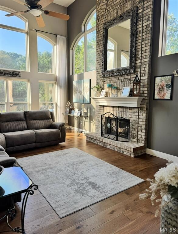 Living area featuring a high ceiling, a ceiling fan, plenty of natural light, and wood-type flooring