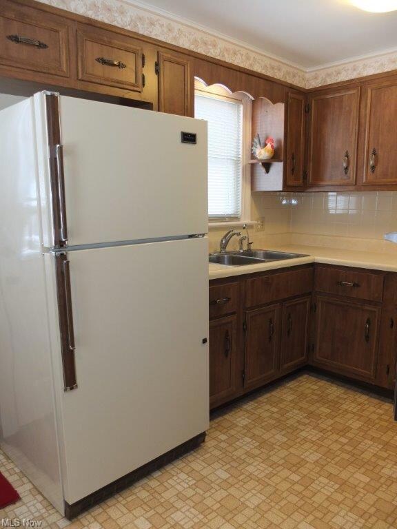 Eat in kitchen with tile backsplash and refrigerat