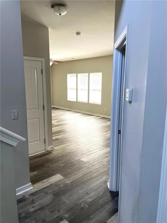 Hall featuring baseboards and dark wood-type flooring