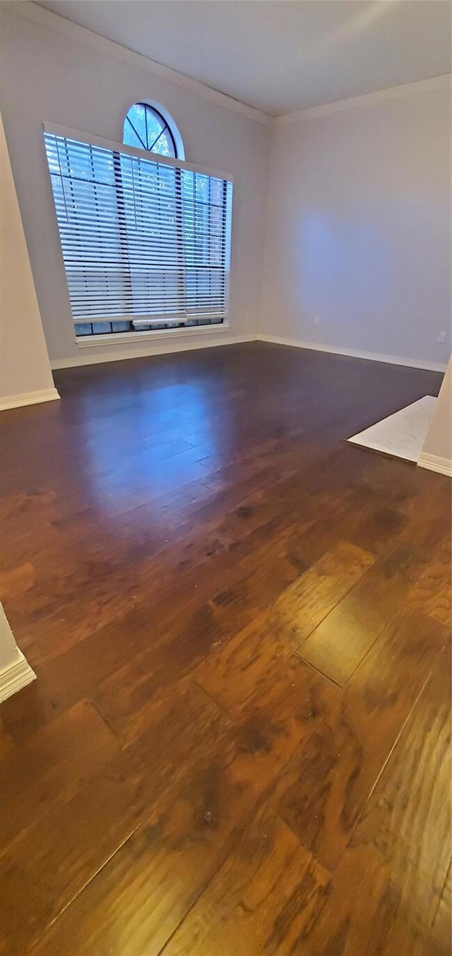 Spare room with crown molding and dark wood-type f
