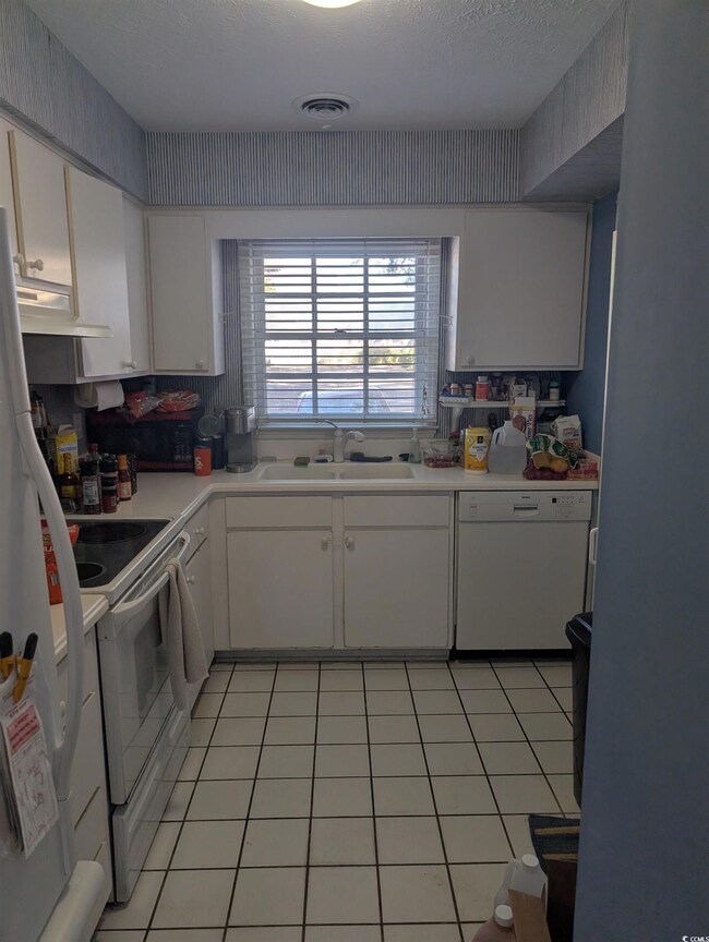 Kitchen with white appliances, white cabinetry, sink, and light tile patterned floors