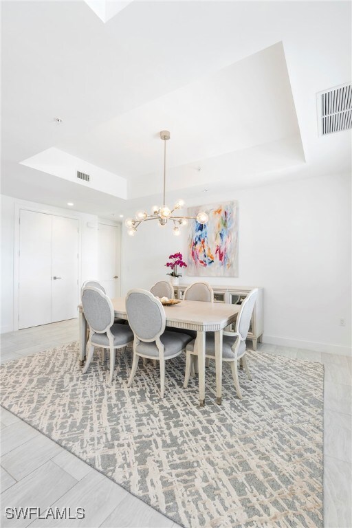 Dining area with a chandelier and a tray ceiling