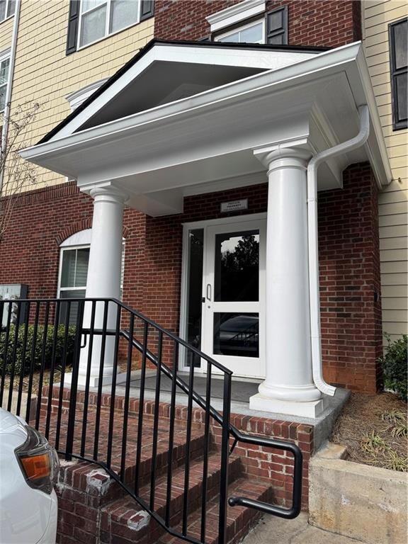 View of exterior entry with a porch and brick sidi