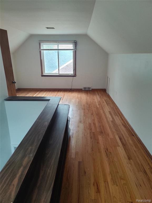 Additional living space featuring lofted ceiling and light wood-style flooring
