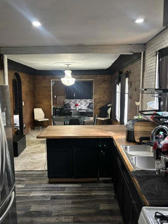 Kitchen featuring dark cabinets, a peninsula, freestanding refrigerator, and dark wood-style flooring