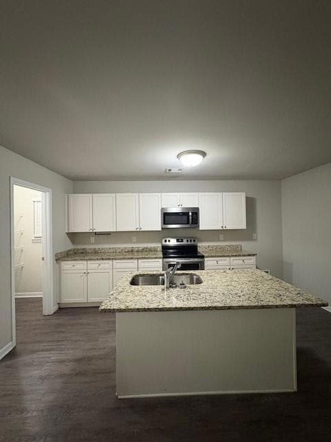 Kitchen featuring white cabinetry, light stone counters, a kitchen island with sink, and stainless steel appliances
