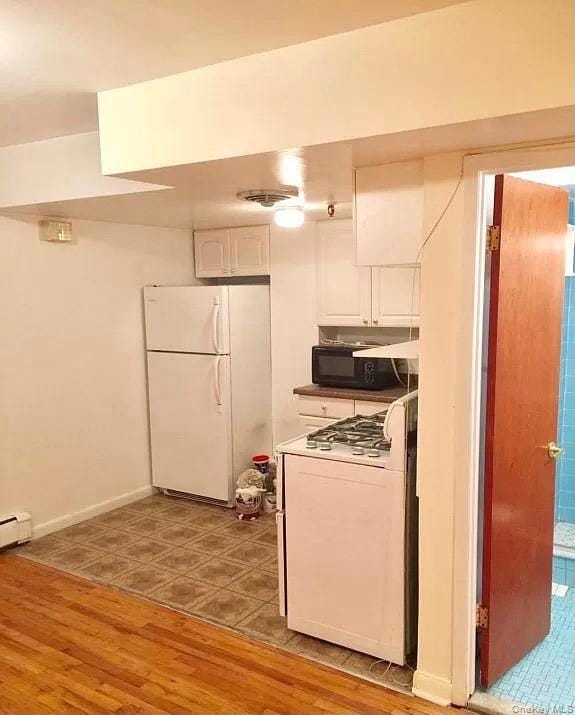 Kitchen featuring white cabinets, white appliances, light wood-type flooring, and a baseboard heating unit