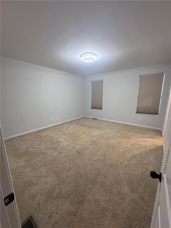 Empty room featuring light carpet and baseboards