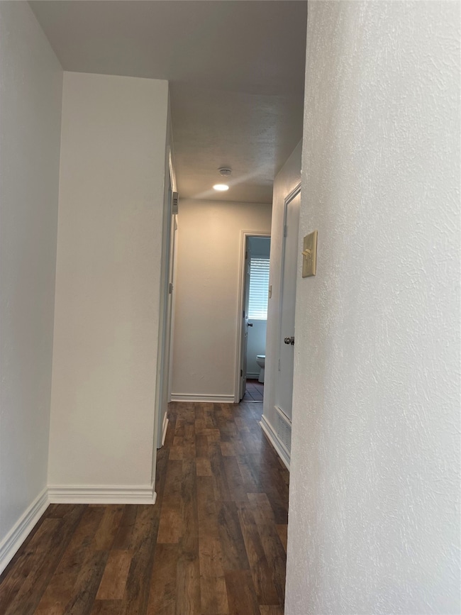 Hall with dark wood-type flooring and a textured wall