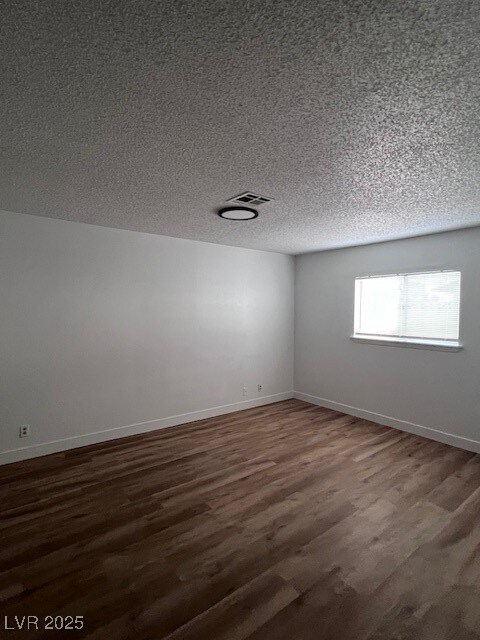 Spare room with dark wood finished floors and a textured ceiling