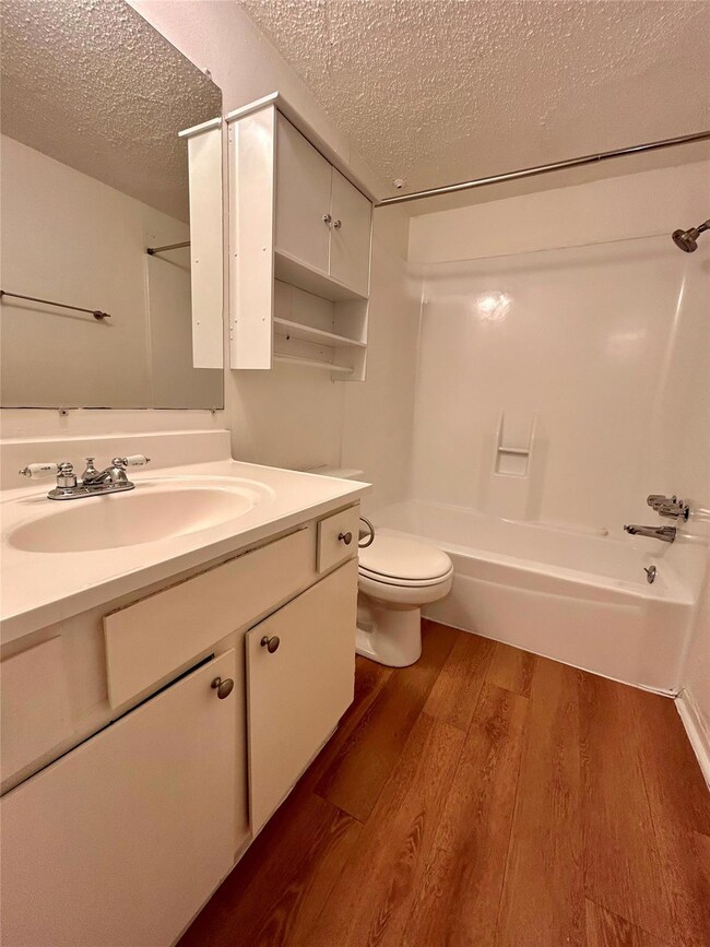 Full bathroom featuring a textured ceiling, wood 