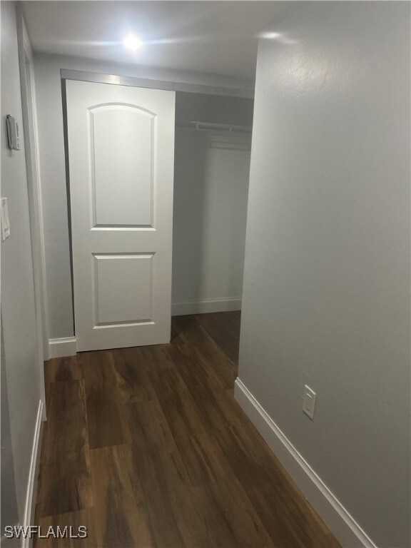 Hallway featuring dark wood-style floors and baseb