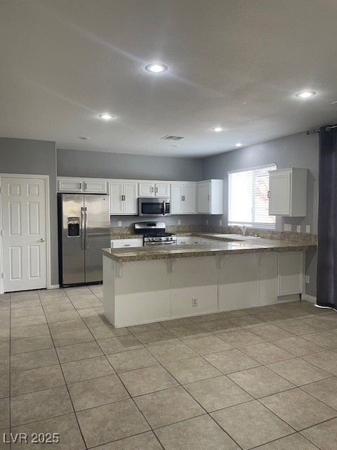 Kitchen with a peninsula, range, white cabinetry,