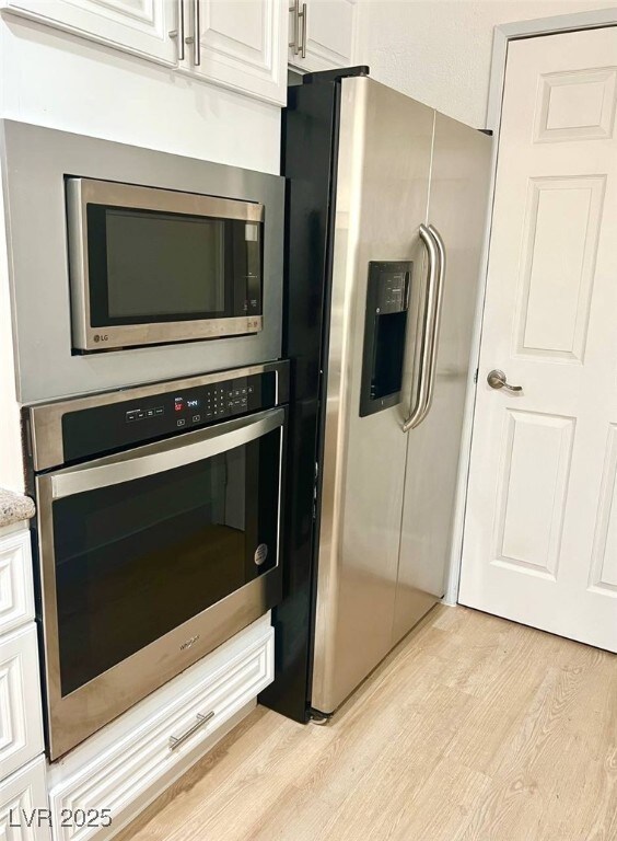 Kitchen with white cabinets, light stone counterto