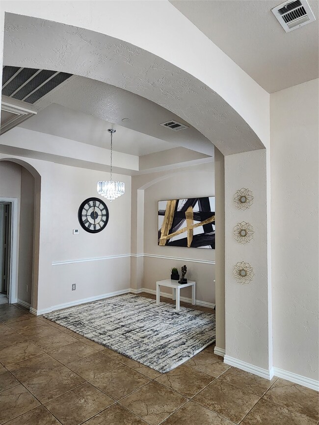 Tiled foyer featuring arched walkways and a chandelier