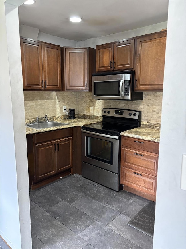 Kitchen featuring a sink, light countertops, decorative backsplash, and stainless steel appliances