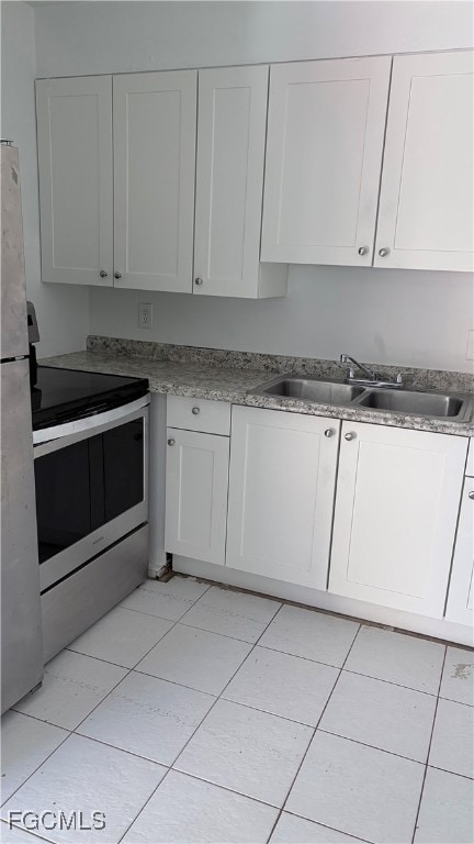 Kitchen with white cabinetry, appliances with stainless steel finishes, light tile patterned floors, and light countertops