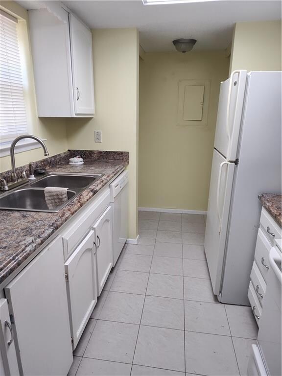 Kitchen featuring refrigerator, white cabinets, dishwashing machine, and light tile patterned flooring